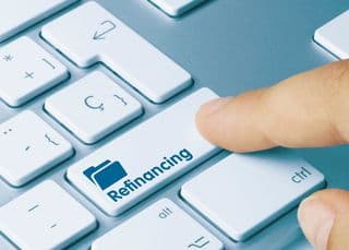 A person clicking on a refinancing button on a keyboard.