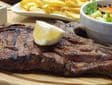 Butter-basted T-bone steak with lime wedge and fries